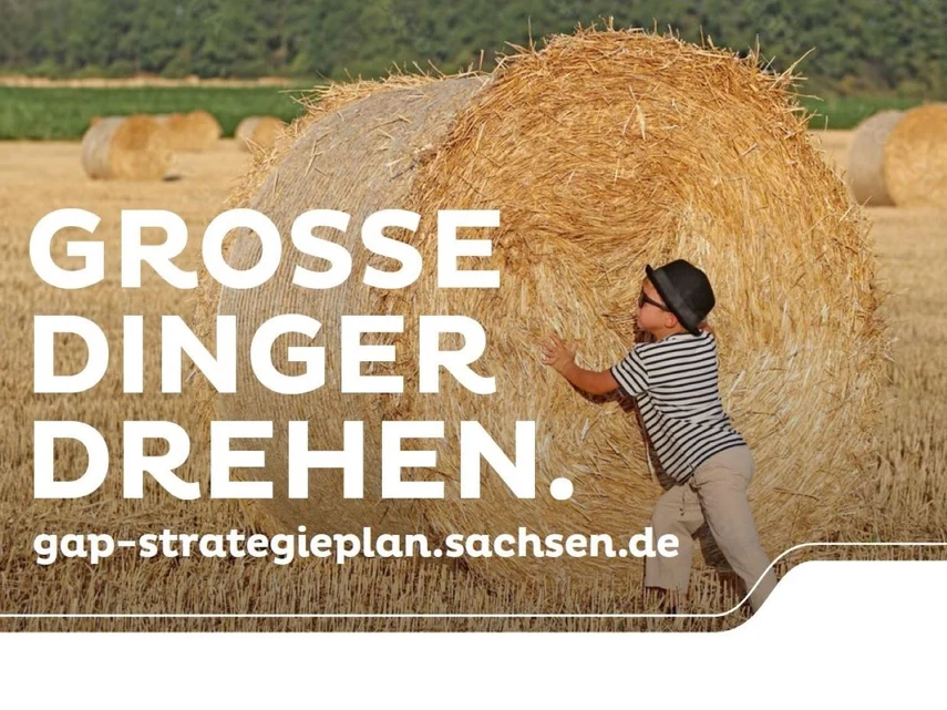 Kleiner Junge dreht großen Strohballen