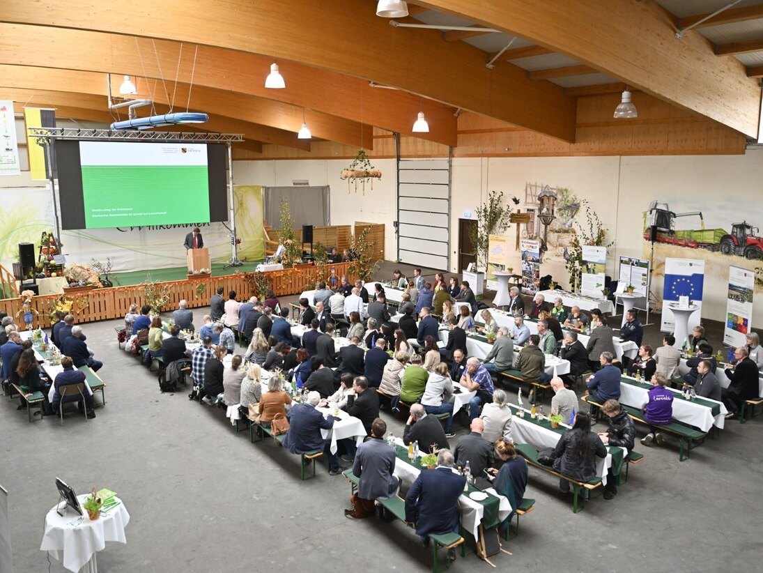 Menschen an Biertischen hören dem Minister zu